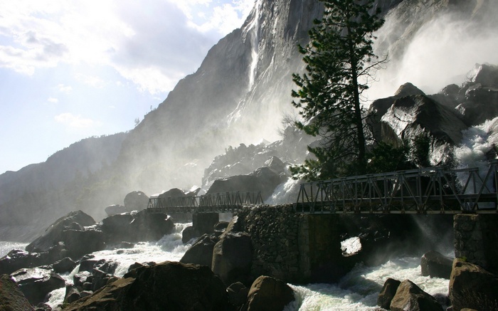 Bridge over a rocky river with a waterfall