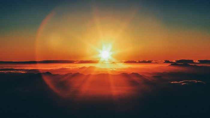 Sunset over mountains with clouds and sun rays
