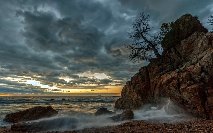 Stormy sky over rocky coastline with crashing waves