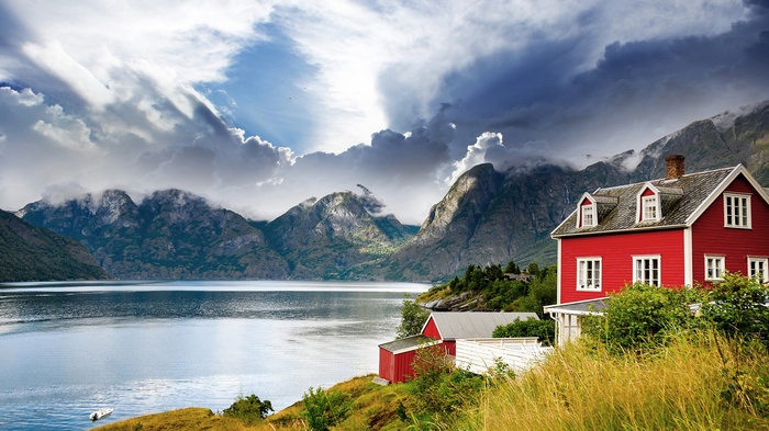 Red house by a fjord with mountains