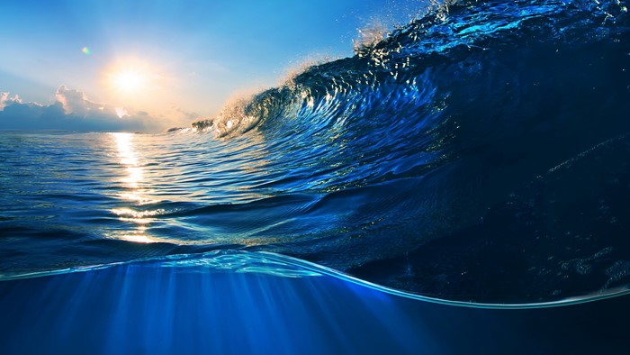 Ocean wave breaking with sunlight and underwater view