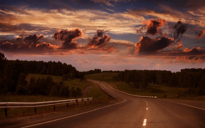 Winding road through rolling hills at sunset