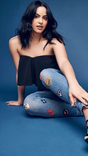 Camila Mendes sitting on blue background