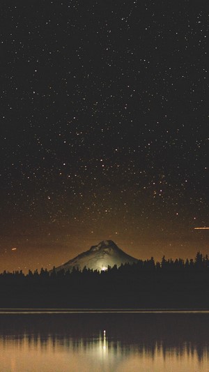 Starry night sky over a mountain and lake