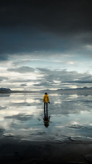Person in Yellow Jacket on Reflective Beach 4K