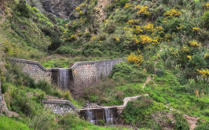 Terraced waterfall with stone walls and green vegetation