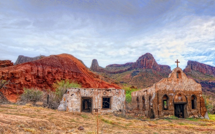Ruined church and building in a desert landscape with mountains
