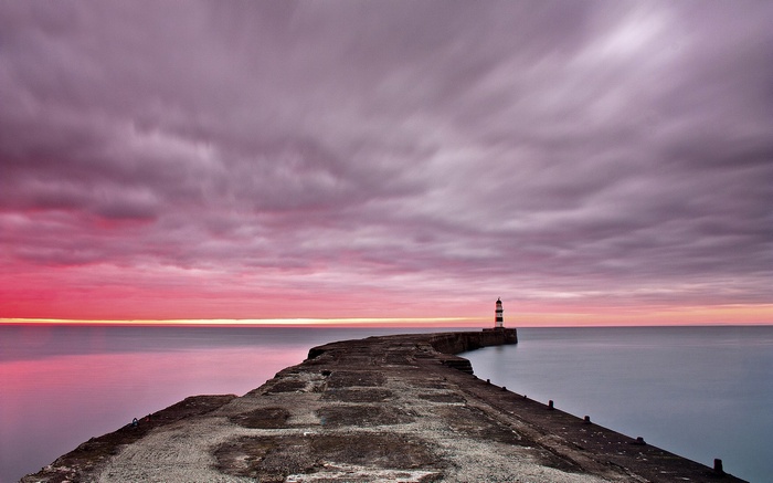 Pier leading to a lighthouse at sunset