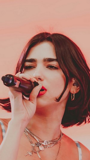 Dua Lipa singing into a microphone