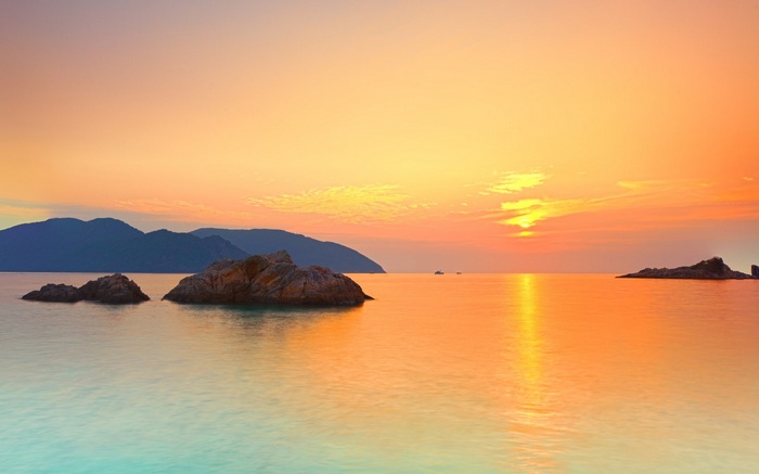 Sunset over the ocean with islands and rocks