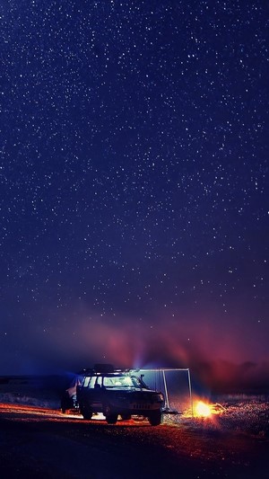 Car camping under a starry night sky with bonfire