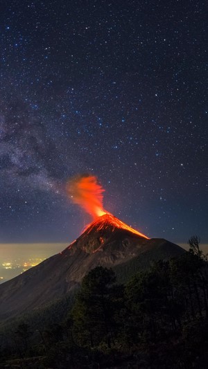 Volcano erupting under a starry night sky