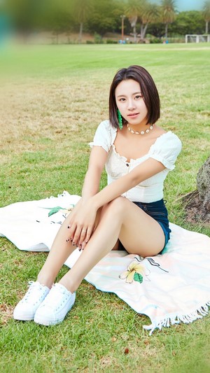 Chaeyoung from TWICE sitting on a blanket in a park