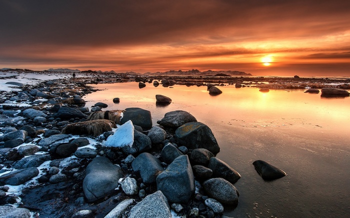 Sunset over rocky beach with snow