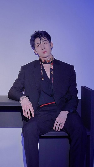 Seungwoo in a black suit with a patterned scarf