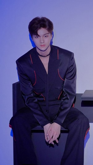 Junho in a black suit with red trim