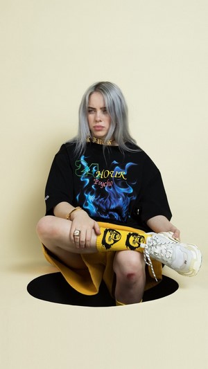 Billie Eilish wearing a black t-shirt and yellow skirt