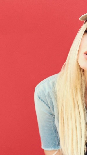 Dove Cameron wearing a denim shirt and a cap