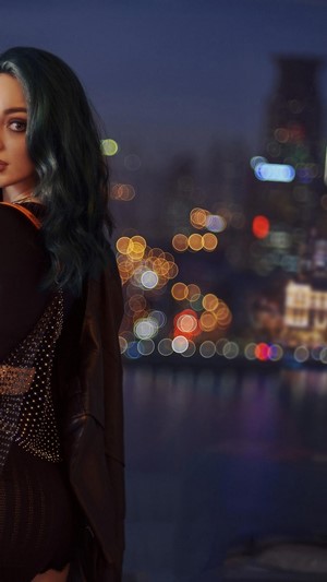 Emma Dumont posing in front of a city skyline at night