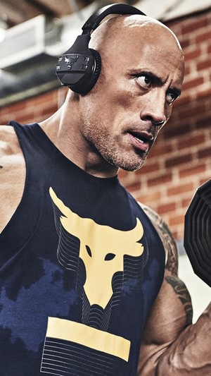 Dwayne Johnson wearing Under Armour headphones and tank top