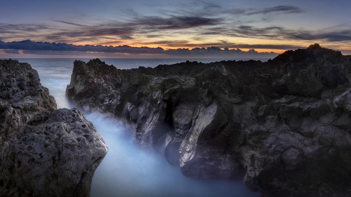 Rocky coastline with ocean waves at sunset
