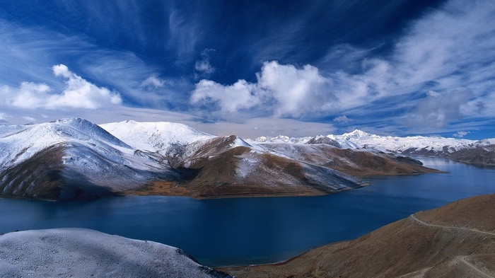 Snow-capped mountains and a blue lake under a cloudy sky
