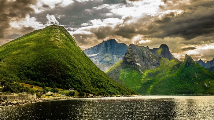 Green mountains and a lake under a cloudy sky