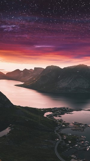 Mountain landscape with a village at sunset and starry sky