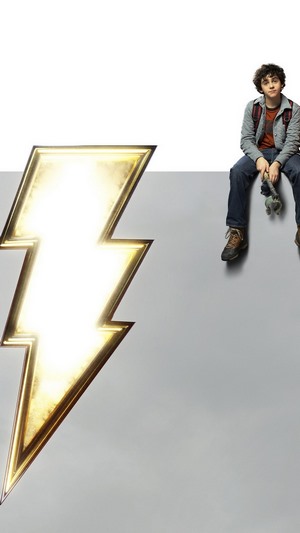 Billy Batson from Shazam sitting next to lightning bolt logo