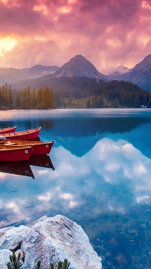 Red boats on a lake with mountains at sunrise