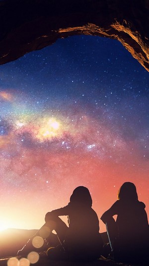 Two people watching the Milky Way under an arch