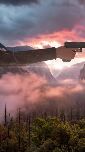 Player holding a gun in a mountainous landscape