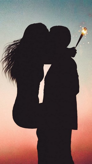 Couple kissing with a sparkler at sunset