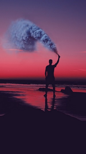 Silhouette with Smoke Flare on Beach at Sunset