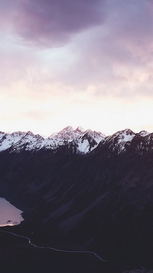 Snow-capped mountains at sunset with a lake