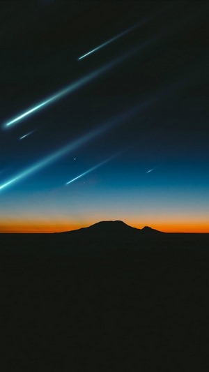 Meteor shower over a mountain at sunset