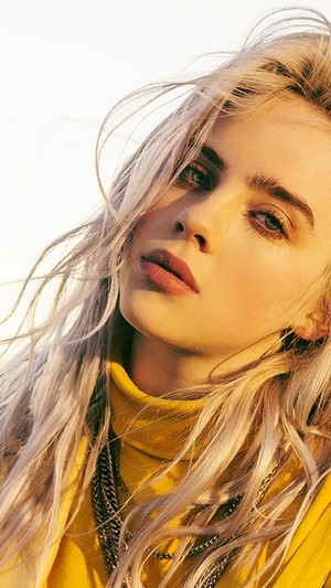 Billie Eilish with blonde hair wearing a yellow turtleneck