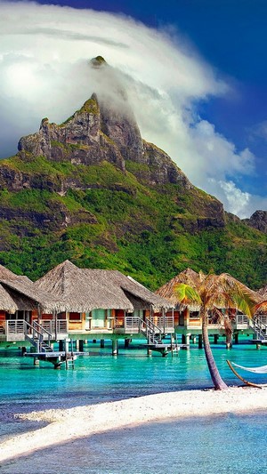 Overwater bungalows in Bora Bora with a mountain backdrop