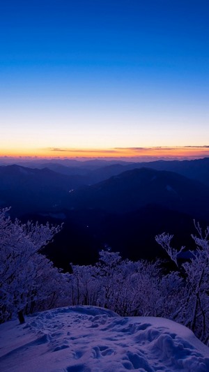 Snowy mountain landscape at dawn with frosted trees