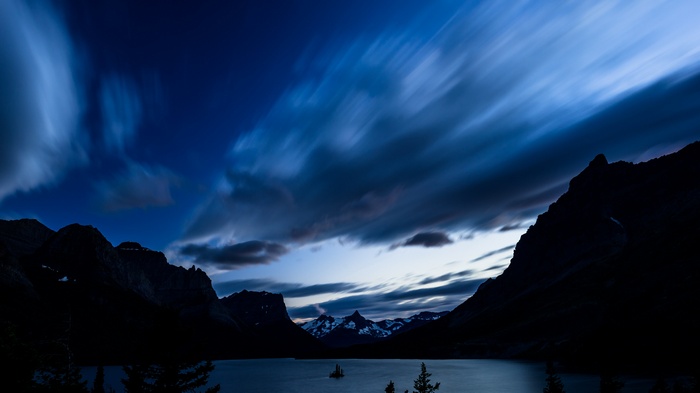 Long exposure of clouds over mountains and lake