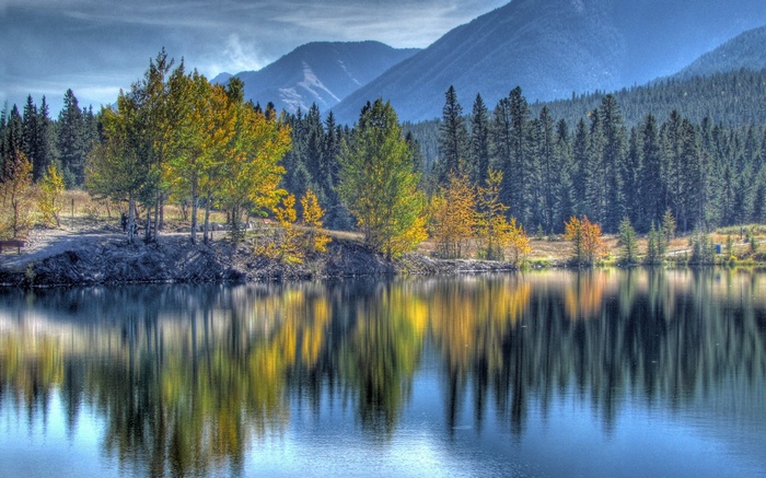 Autumn trees reflected in a calm lake with mountains