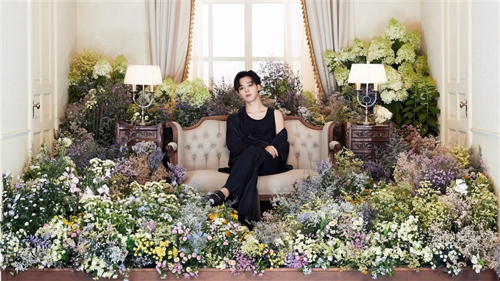 Jimin from BTS sitting on a couch surrounded by flowers