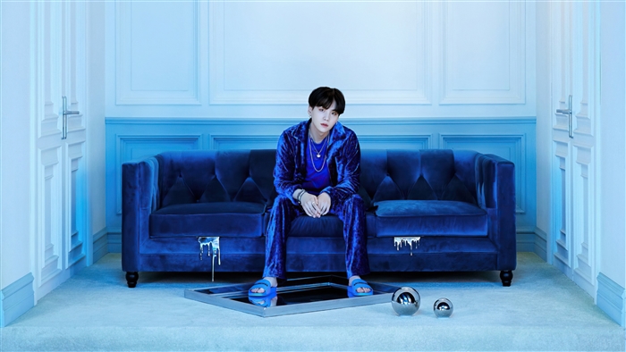 Suga from BTS sitting on a blue couch