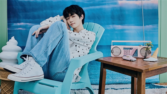 Beomgyu from TXT sitting in a chair with a retro radio