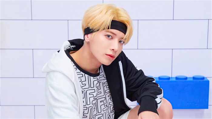 Taehyun from TXT wearing a black headband and white hoodie