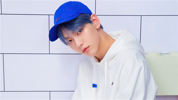 Soobin from TXT wearing a blue cap and white hoodie