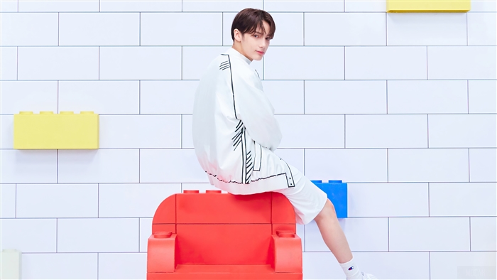Huening Kai from TXT sitting on a red Lego chair