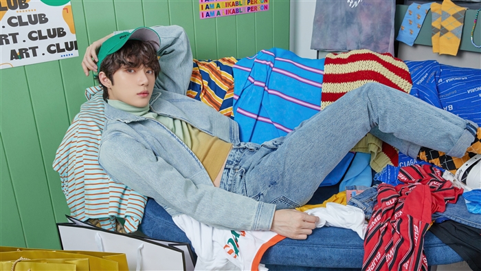 Choi Beomgyu from TXT in a colorful, cluttered room