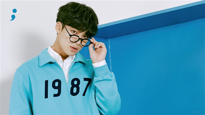 Kim Min Gyu from Seventeen wearing glasses and a blue sweatshirt