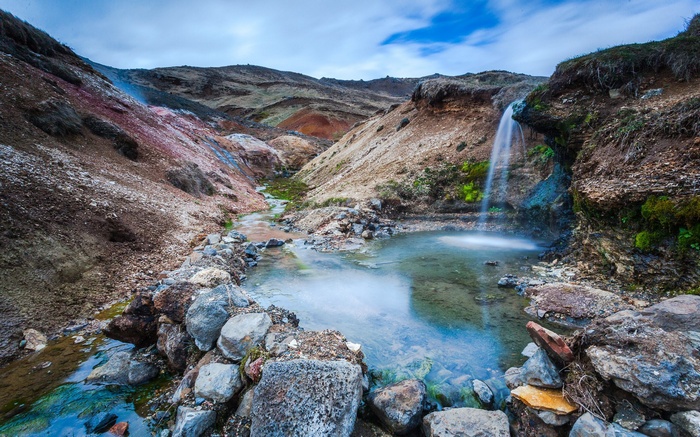 Geothermal landscape with hot springs and waterfall
